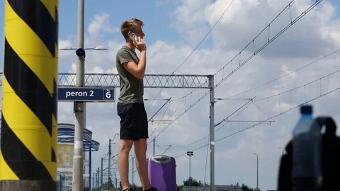 Young man smiling to the camera while chatting on cellphone and standing  Stock Footage 78652435
