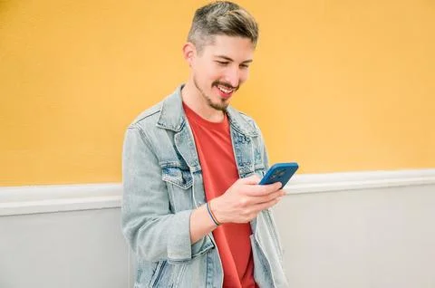 Young man smiling confident using smartphone at street Stock Photos