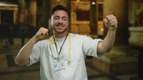 Young man, smiling doctor with beard and stethoscope, stands indoors at a c.. Stock Footage 310457581