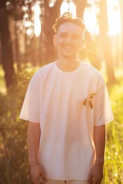 Young man smiling in a forest bathed in golden hour sunlight Stock Photos
