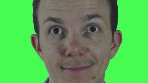 Young man smiling gently with direct eye contact against chroma green background Stock Footage 311001255