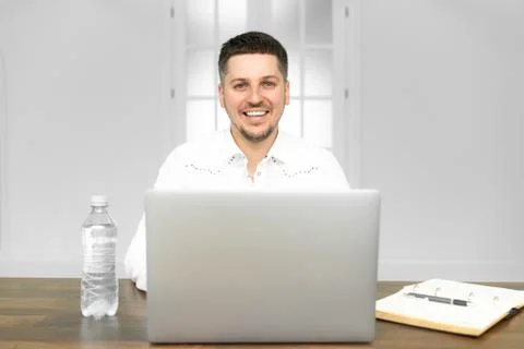 Young man smiling as he reads the screen of a laptop computer while relaxing 스톡 사진
