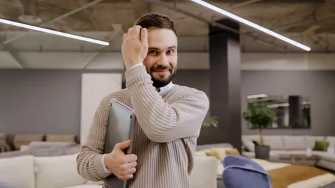 Young man smiling holding laptop in modern furniture store Stock Footage 322550127