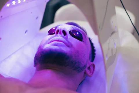 Young man smiling in solarium while getting suntan Stock Photos