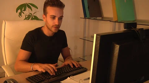 Young man, smiling, talking and working on computer. Video stock 31656037