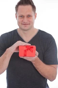 Young man smiling while holding a red gift box Stock Photos