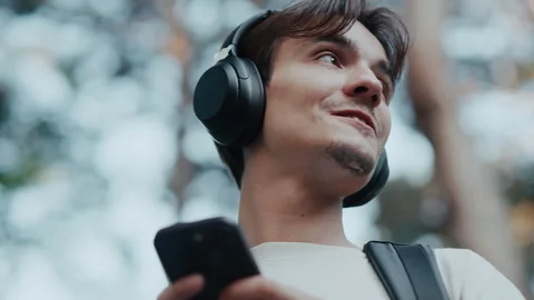 Young man smiling while listening to music on smartphone outdoors in forest Stock Footage 339216280