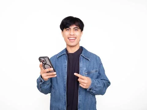 Young man smiling while pointing at his smartphone in a bright studio, idea.. Stock Photos