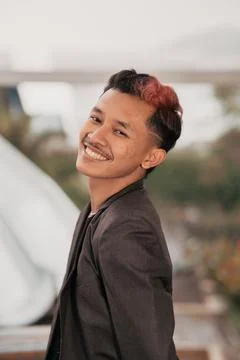 Young man smiling while posing in a dark blazer outdoors Stock Photos