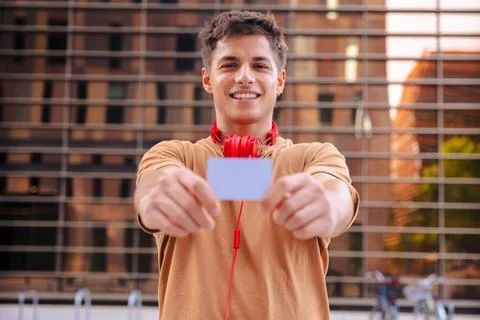 Young man smiling while showing a blank business card to the camera outdoors Stock Photos