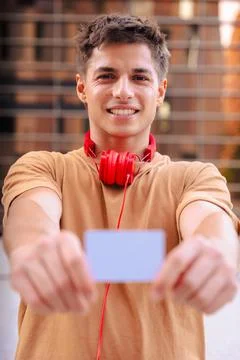 Young man smiling while showing a blank business card to the camera outdoors Stock Photos