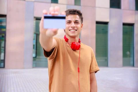 Young man smiling while showing a blank business card to the camera outdoors Stock Photos