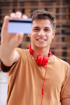 Young man smiling while showing a blank business card to the camera outdoors Stock Photos