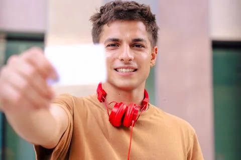 Young man smiling while showing a blank business card to the camera outdoors Stock Photos