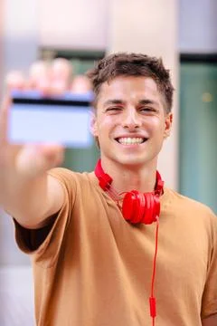 Young man smiling while showing a blank business card to the camera outdoors Stock Photos