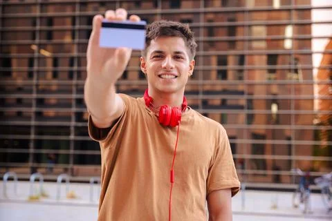 Young man smiling while showing a blank business card to the camera outdoors Stock Photos