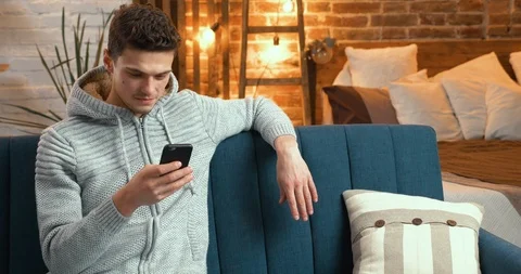 Young Man smiling while using his Phone, ordering Porterage at Home. Attractive Stock-Footage 126229130