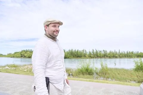 Young man smiling while walking along the Limay River promenade in Neuquen. Stock Photos