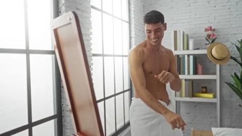 Young man smiling while wrapped in a towel dances enthusiastically in a mod.. Stock Footage 303414600