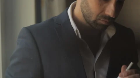 Young man smokes a cigarette at the window Stock-Footage 61213469