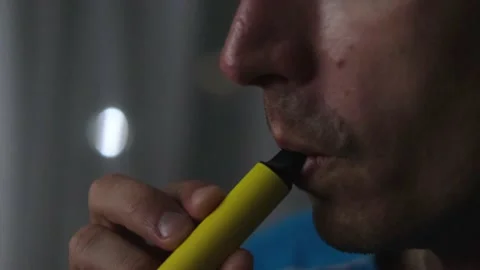 Young man smokes disposable electronic cigarettes . Stock Footage 164388761