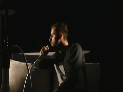 The young man smokes a hookah alone on black background. slow motion Stock-Footage 82682609
