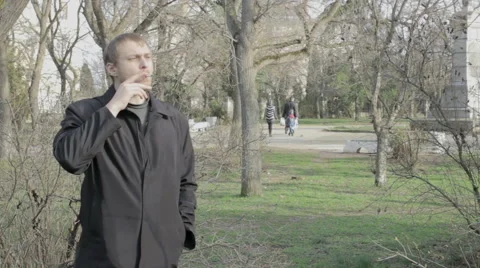 Young man smokes at a park Video stock 59856810