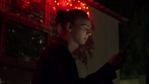 Young man smoking and using smartphone outdoors at night 3 Video stock 95863866