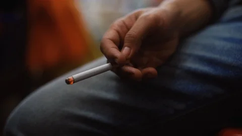 Young man smoking cigarette put his hand on the knee. Stock Footage 93494068