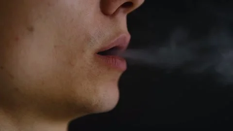 Young man smoking an electronic cigarette, close-up of lips exhaling vapor Stock Footage 295780065