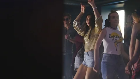 A young man smoking a hookah next to dancing girls Stock Footage 75287317