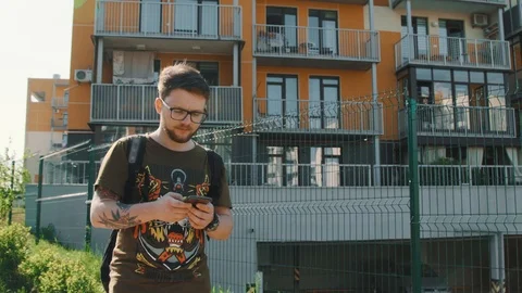 Young man sms texting using app on smart phone at city, summer Stock Footage 89576048