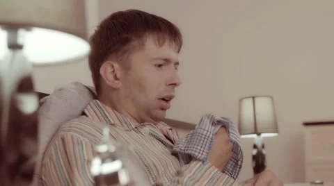 Young man sneezing and using his handkerchief to blow his nose Видео 68421043