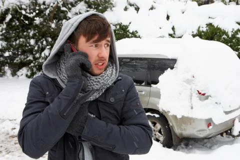 Young man in snow with broken down car Stock Photos