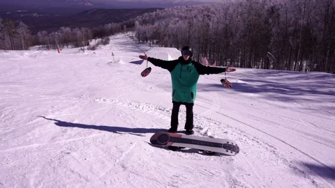 A young man snowboarder standing with his snowboard on a snow covered mountain Stock Footage