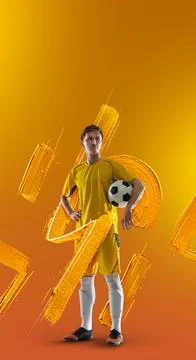 Young man, soccer footbal player standing with ball isolated over orange color Stock Photos