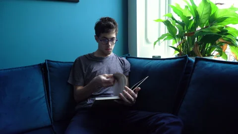 Young Man on Sofa Reading a Book Stock Footage 274188248