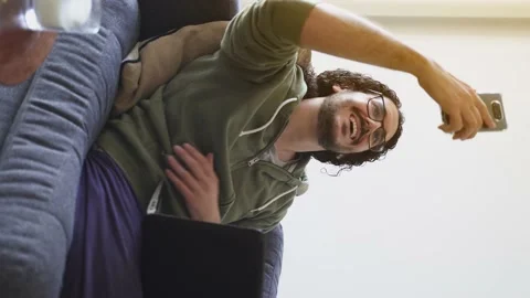 Young man on the sofa taking selfie while using laptop Stock Footage 164906354