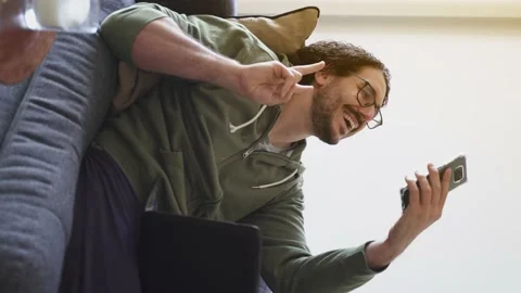 Young man on the sofa taking selfie while using laptop Stock Footage 164906449