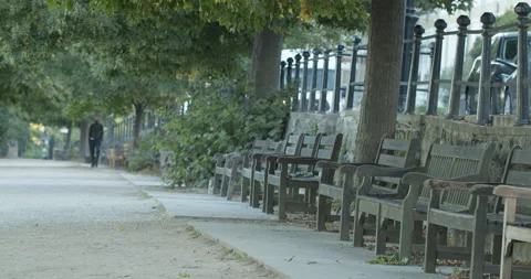 A young man in soft focus of long shot walks past row of empty benches Stock-Footage 150373955