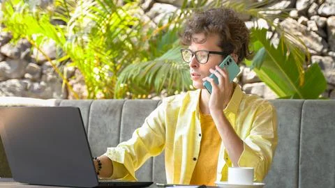 Young man solving work-related issues on the phone while sitting in a cafe Stock Photos