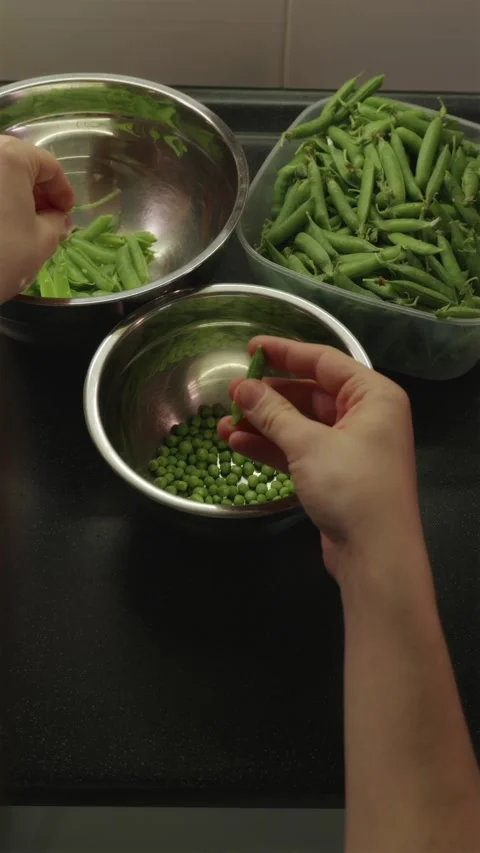 Young man sorting fresh green pea pods on kitchen table Stock Footage 338395337