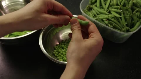 Young man sorting freshly harvested green pea pods at kitchen counter Stock Footage 338395398