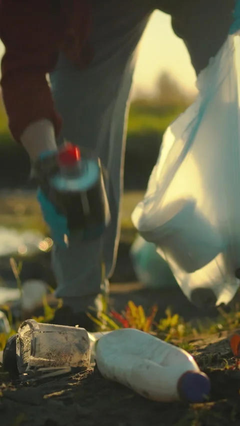 Young man sorts plastic waste for environmental cleanup in a rural area duri Stock Footage 331742527