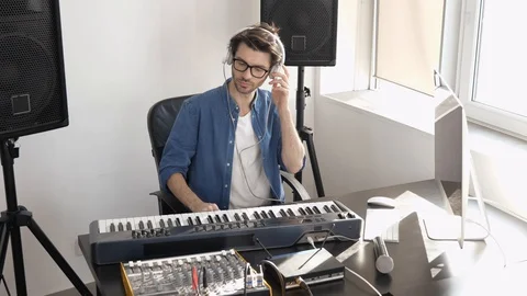 Young man in sound recording studio. Sit in front keyboard and adjusting sound Stock Footage 128936340