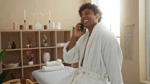Young man in a spa talking on a phone while wearing a white robe in a welln.. 스톡 동영상 292130285