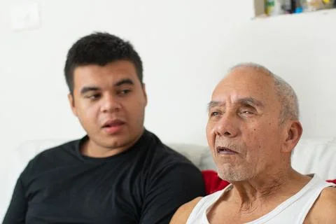 Young man speaking while elderly father listens showing communication and c.. Stockfoto's