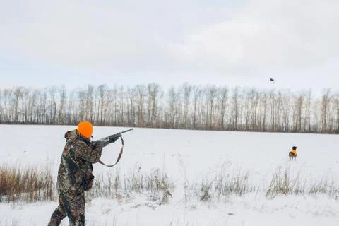 Young man in speccial clothes aiming at flying bird while hunting Фото