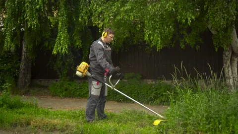 A young man from the special services mows the lawn with a petrol trimmer. A man Stock Footage 200848355