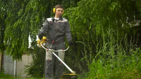A young man from the special services mows the lawn with a petrol trimmer. A man Stock Footage 200848376
